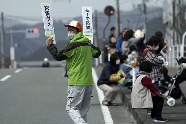 Мужчина с табличками во время эстафеты Олимпийского огня в Токио-2020 в префектуре Фукусима, Япония - Sputnik Қазақстан