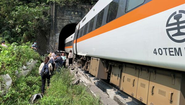 Люди идут рядом с поездом, который сошел с рельсов в туннеле к северу от Хуаляня, Тайвань, 2 апреля 2021 года - Sputnik Казахстан