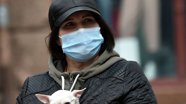 Женщина в маске прогуливается по улице с собачкой за пазухой  - Sputnik Казахстан