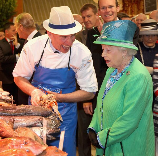 Королева Великобритании Елизавета II разговаривает с торговцем рыбой Пэт О’Коннелл во время посещения английского рынка в Корке в последний день своего четырехдневного визита в Ирландию, 20 мая 2011 года. - Sputnik Казахстан