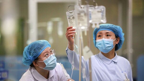 Медсестры в защитных костюмах поправляют капельницы в больнице с коронавирусом - Sputnik Казахстан