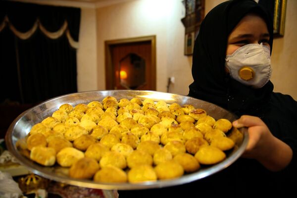 Иракская женщина несет печенье в первый день праздника Ид-аль-Фитр в Басре, Ирак - Sputnik Қазақстан