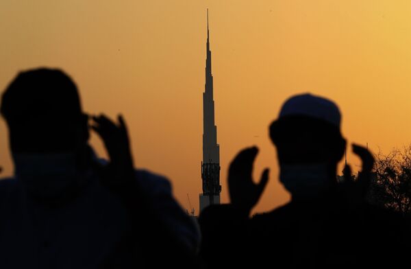 На фоне самого высокого здания в мире, Бурдж-Халифа, мусульманские мужчины в масках молятся, Дубай - Sputnik Казахстан