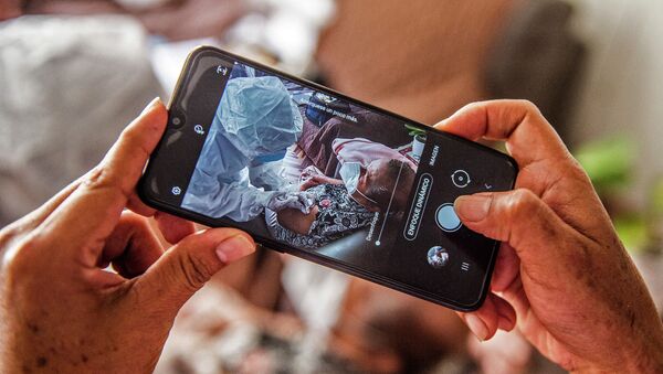 Человек снимает на смартфон, как врач осматривает пациента с коронавирусом  - Sputnik Қазақстан