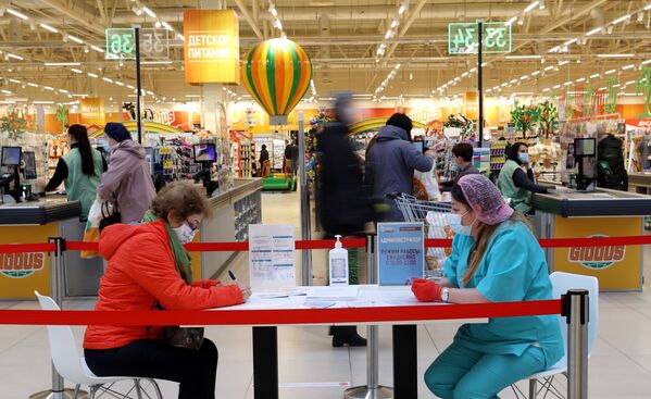 Женщина заполняет документы перед вакцинацией от COVID-19 российской вакциной Спутник V (Гам-КОВИД-Вак) в гипермаркете Глобус в Москве - Sputnik Казахстан