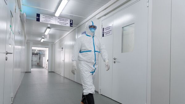 Медик в защитном костюме идет по коридору больницы с коронавирусом - Sputnik Қазақстан
