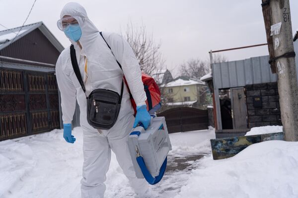 Медик в защитном костюме идет навестить пациента с коронавирусом на дому - Sputnik Казахстан