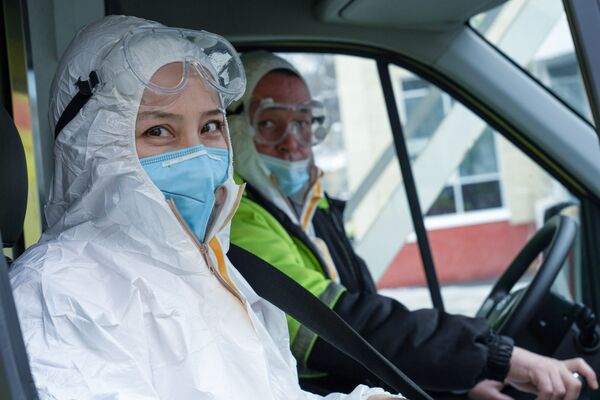 Медики в защитных костюмах выезжают на вызов на машине скорой помощи - Sputnik Қазақстан