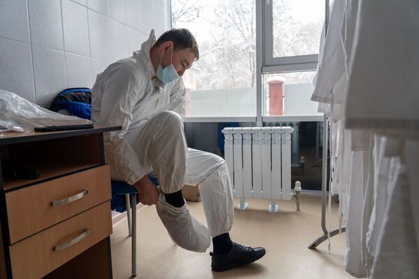 Медик надевает защитный костюм перед началом смены в больнице с коронавирусом  - Sputnik Қазақстан