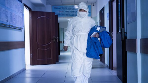 Медик в защитном костюме идет по коридору больницы  - Sputnik Қазақстан