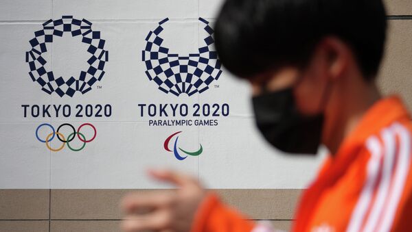 Мальчик в маске проходит мимо логотипов Олимпиады в Токио - Sputnik Казахстан