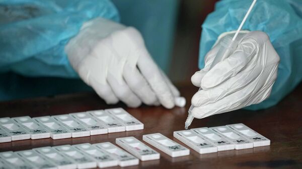 Медик в защитном костюме проводит анализ проб ПЦР-теста на коронавирус - Sputnik Казахстан