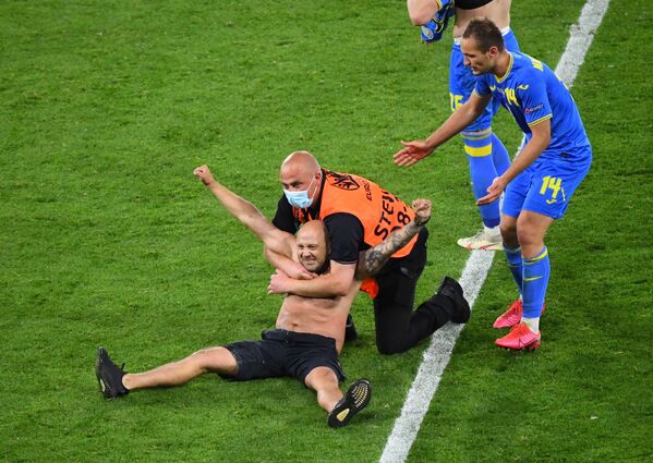 Охрана с выбежавшим на поле мужчиной во время матча Швеция-Украина на ЕВРО-2020 - Sputnik Қазақстан