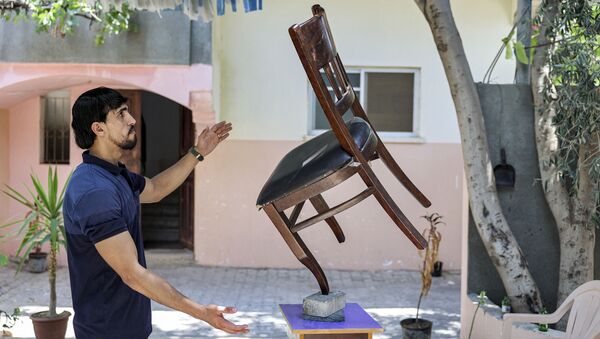 Палестинец во время балансировки стула на кирпиче в городе Бейт-Лахия - Sputnik Казахстан