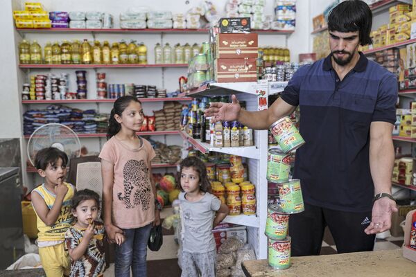 Палестинец во время балансировки консервов друг на друге в городе Бейт-Лахия - Sputnik Казахстан