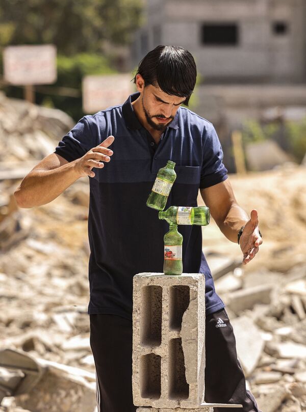 Палестинец во время балансировки бутылок на камне в городе Бейт-Лахия - Sputnik Қазақстан