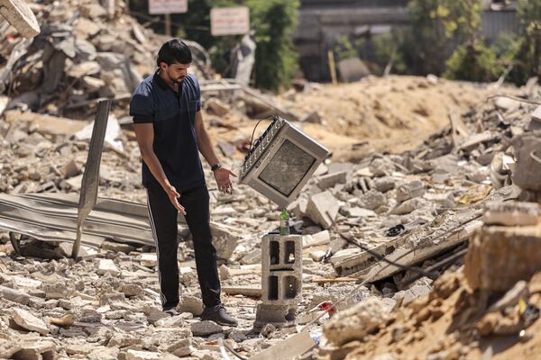 Палестинец во время балансировки телевизора на бутылке  в городе Бейт-Лахия - Sputnik Қазақстан