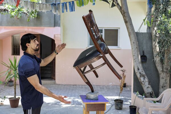 Палестинец во время балансировки стула на кирпиче в городе Бейт-Лахия - Sputnik Қазақстан
