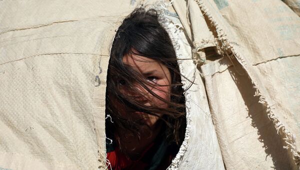 Афганская девочка выглядывает сквозь прореху в палатке в лагере беженцев  - Sputnik Қазақстан