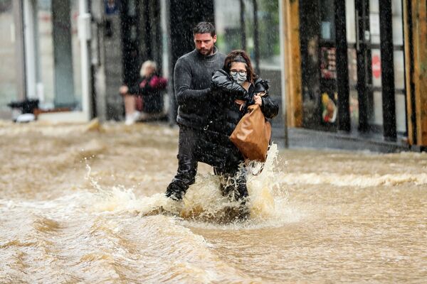 Мужчина помогает женщине пройтись по затопленной улице в городе Спа, Бельгия - Sputnik Казахстан