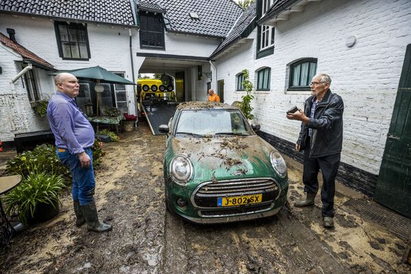 Жители стоят во дворе, покрытом грязью после сильного дождя в Херлене, Нидерланды - Sputnik Қазақстан