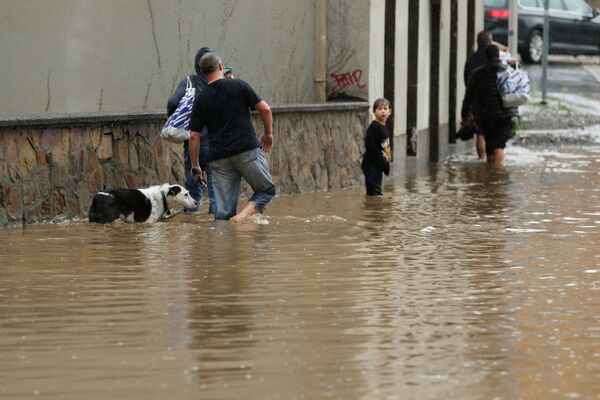Люди идут по затопленной улице после проливных дождей в Хагене, Германия - Sputnik Казахстан