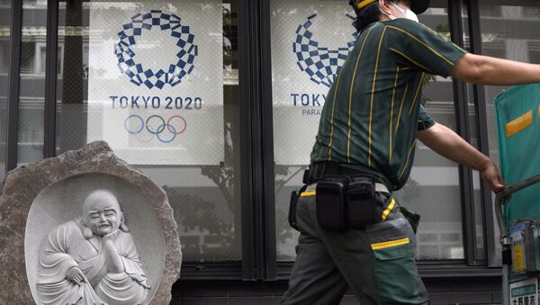 Курььер напротив постеров Олимпиады и Паралимпиады-2020 в Токио   - Sputnik Казахстан