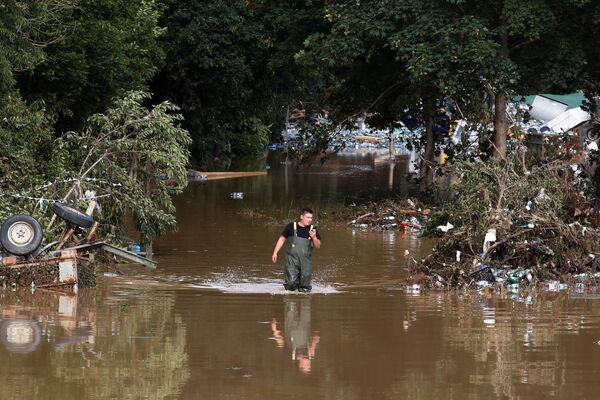 Мужчина идет по затопленному району, пострадавшему от наводнения после проливных дождей, в Бад-Нойенар-Арвайлере, Германия - Sputnik Казахстан