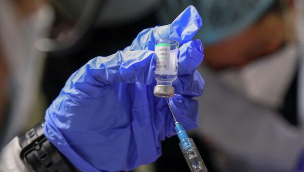 Медик в защитном костюме набирает в шприц вакцину от коронавируса  - Sputnik Қазақстан