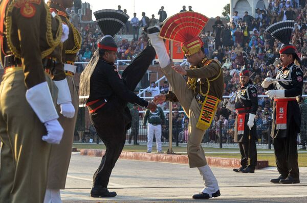 Индийские пограничники в коричневой форме и пакистанские рейнджеры в черной форме выступают во время церемонии  на индийско-пакистанском пограничном посту Вагах - Sputnik Казахстан