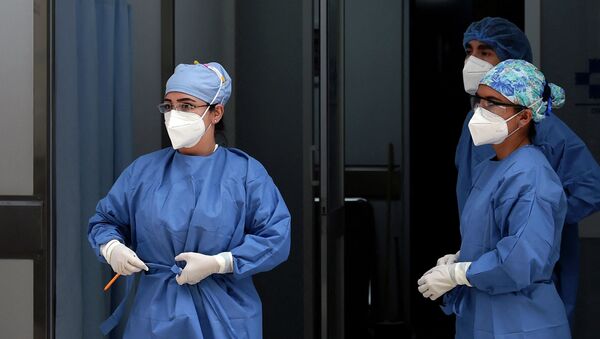 Медики в защи тных костюмах готовятся принять пациента на скорой в больнице с коронавирусом  - Sputnik Казахстан