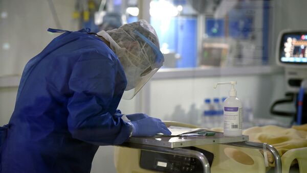 Врач в защитном костюме работает с документами в отделении реанимации больницы с коронавирусом - Sputnik Қазақстан