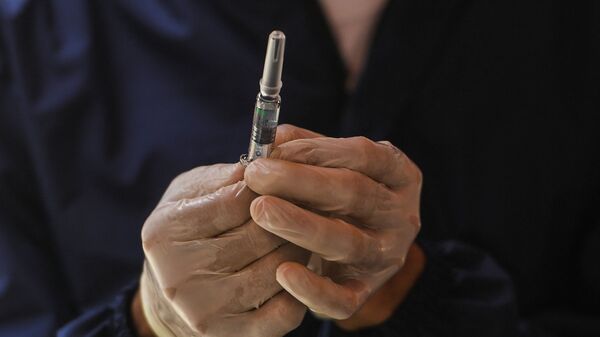Медицинский работник показывает предварительно заполненный шприц вакцины Vero Cell Covid-19 китайского производства - Sputnik Казахстан