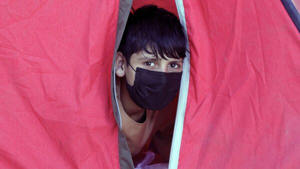 Ребенок выглядывает из импровизированной палатки в лагере для беженцев  - Sputnik Казахстан