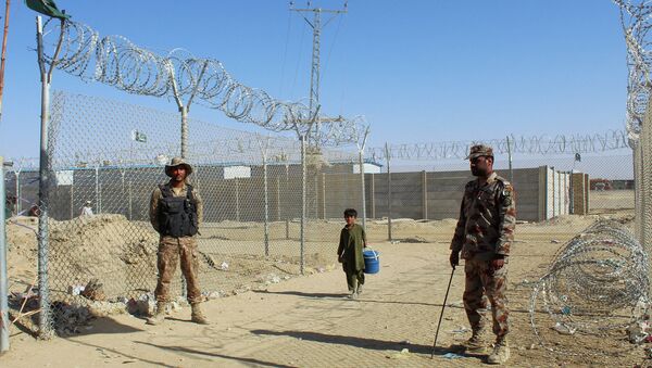 Афганский мальчик проходит мимо пакистанских военных, охраняющих границу между странами  - Sputnik Казахстан
