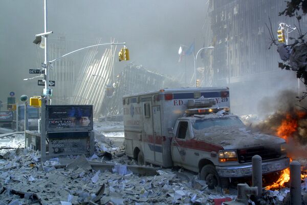 Поврежденный автомобиль скорой помощи и покрытая обломками улица после обрушения первого здания Всемирного торгового центра в Нью-Йорке - Sputnik Казахстан
