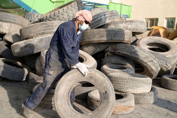 Рабочий готовится утилизировать шину на заводе по переработке шин в районе Аль-Салми, Кувейт - Sputnik Қазақстан