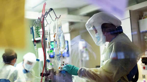 Медик в защитном костюме проверяет апааратуру в отделении реанимации в больице с коронавирусом  - Sputnik Казахстан