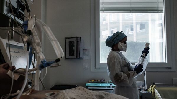 Медсестра в защитном костюме готовит лекарства для капельницы пациенту в палате реанимации больницы с коронавирусом  - Sputnik Казахстан