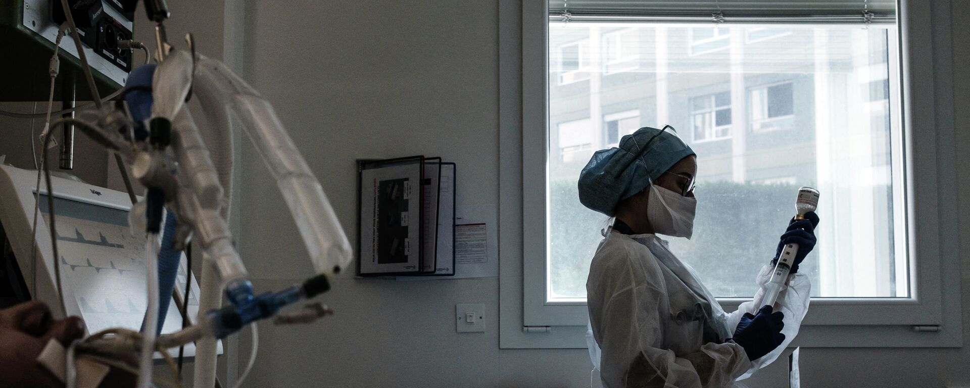 Медсестра в защитном костюме готовит лекарства для капельницы пациенту в палате реанимации больницы с коронавирусом  - Sputnik Қазақстан, 1920, 24.11.2021