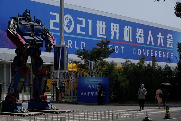 Мужчина в маске проходит мимо Всемирной конференции роботов, проходящей в Пекине, Китай, в пятницу, 10 сентября 2021 г. (AP Photo / Ng Han Guan) - Sputnik Казахстан