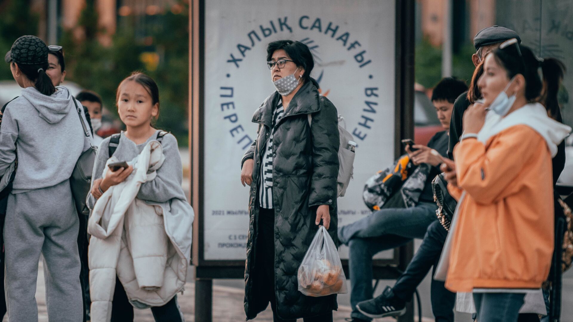 Люди стоят на остановке на фоне лайтбокса с логотипом национальной переписи населения  - Sputnik Қазақстан, 1920, 07.12.2021