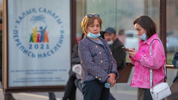 Люди стоят на остановке на фоне лайтбокса с логотипом национальной переписи населения - Sputnik Казахстан