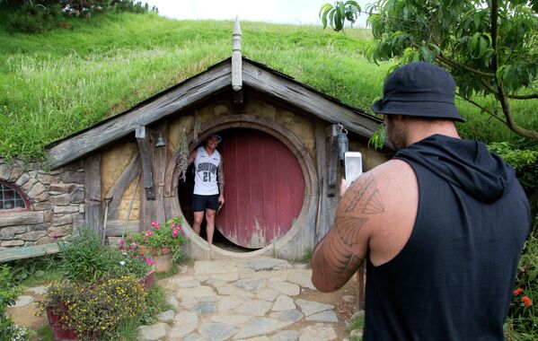 Турист фотографируется возле домика хоббита в Новой Зеландии  - Sputnik Казахстан