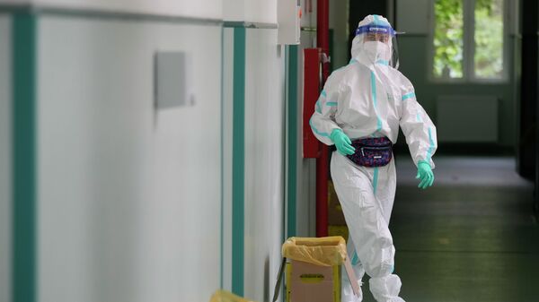 Медик в защитном костюме идет по коридору больницы с коронавирусом  - Sputnik Казахстан
