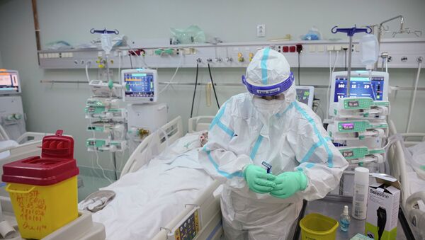 Медработник в защитном костюме ухаживает за пациентом в отделении интенсивной терапии в больнице с коронавирусом  - Sputnik Қазақстан