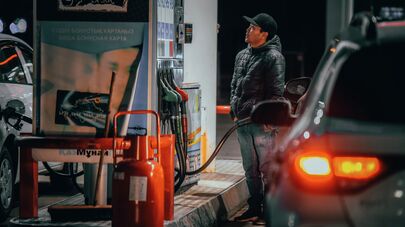 Автолюбитель следит за наполнением бензобака на АЗС