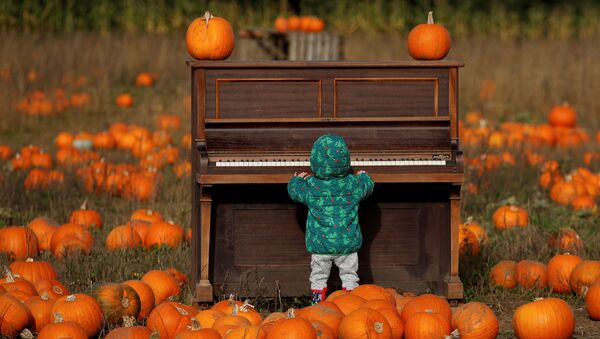 Ребенок играет на пианино на тыквенном поле фермы Pop Up Farm в Великобритании в преддверии Хэллоуина - Sputnik Казахстан