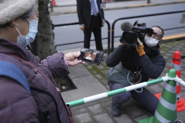 Женщина смотрит трансляцию пресс-конференции бывшей принцессы Мако и ее мужа Кэй Комуро в Токио  - Sputnik Қазақстан