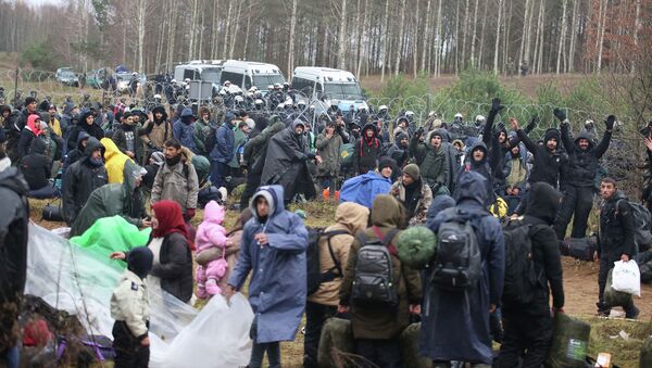 На снимке, сделанном 8 ноября 2021 года, видны мигранты на белорусско-польской границе. 8 ноября Польша заявила, что сотни мигрантов в Беларуси спускаются на ее границу с целью прорваться в страну-члена ЕС, что НАТО назвало умышленной тактикой Минска. Леонид Щеглов / БЕЛТА / AFP - Sputnik Казахстан